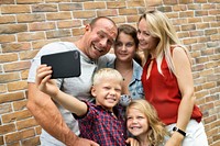 Family taking a selfie by a brick wall