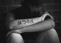 Girl with hashtag sad written on her arm
