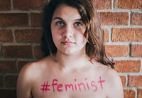 Girl with hashtag feminist written on her chest