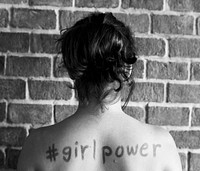 Girl with hashtag girl power written on her back
