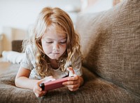 Little girl playing a mobile game on the couch