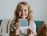 Little girl showing a photo from an instant camera