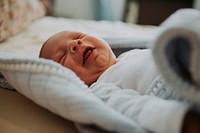 Infant baby on a bed yawning