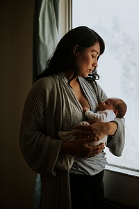 Mother holding her baby indoors