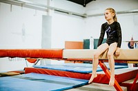 Young gymnast sitting on a balance beam