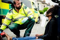 Male paramedic putting on an oxygen mask to an injured woman on a road