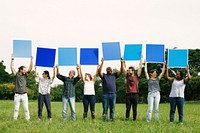 Diverse people holding blue squared boards in the park