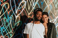 Happy couple posing for the camera against the backdrop featuring the graffiti artwork by James Goldcrown in Los Angeles, USA, 13 July 2018 