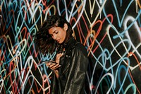 Beautiful woman using a phone against the backdrop featuring the graffiti artwork by James Goldcrown in Los Angeles, USA, 13 July 2018 