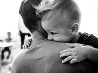 Father carrying his son into a classroom