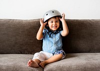 Little boy sitting on a sofa and wearing a helmet