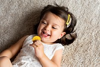 Smiling girl holding a bitcoin laying on carpet