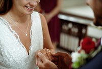 Groom putting on the wedding ring on his bride