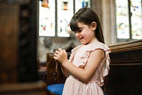 Little catholic girl praying with a rosary in her hands