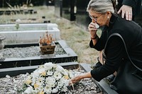 Old woman laying flowers on a grave