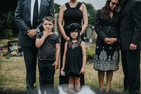 Sad grandkids standing by the grave