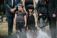 Sad grandkids standing by the grave