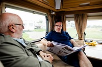 Senior men discussing the newspaper in a trailer