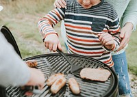 Mother assisting her child while grilling
