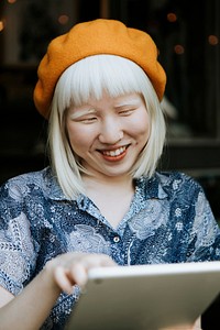 Sweet albino woman using a digital tablet at a cafe