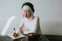 Cute albino woman writing in her journal at a cafe
