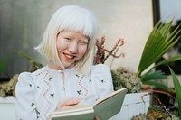 Cute albino girl reading a book in her backyard