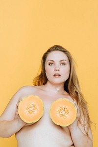 Blond woman holding cantaloupes over her breasts