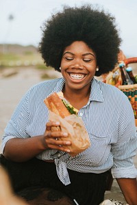Woman eating a sandwich at a beach picnic
