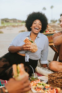 Woman eating a sandwich at a beach picnic