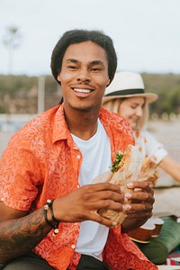 Man eating a sandwich at a beach picnic