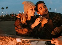 Couple having a s'more at the beach