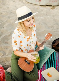 Blond girl playing ukulele for her friends at the beach