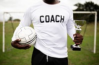 Soccer coach holding a trophy cup and ball