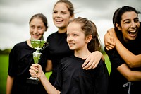 Young female football players holding a winning cup