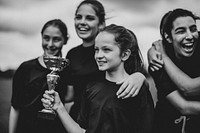 Young female football players holding a winning cup