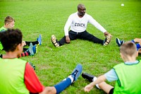 Football coach stretching with junior players