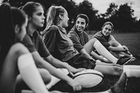 Happy female rugby players sitting on the grass