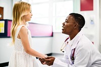 Friendly pediatrician talking to her little patient