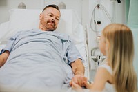 Daughter holding fathers hand in the hospital