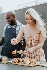 Diverse friends making barbeque skewers at a party