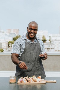 Chef seasoning barbeque skewers at a rooftop party