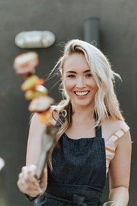 Cheerful woman cooking a barbeque skewer