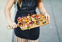 Woman serving vegan barbecue skewers on a wooden board