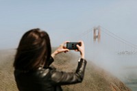 Woman taking a photograph of the Golden Gate Bridge, San Francisco
