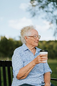 Happy senior woman having a takeaway coffee at the park