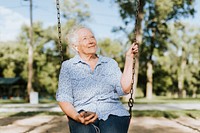 Cheerful senior woman listening to music at a playground