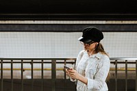 Girl listening to music while waiting for a train at a subway platform