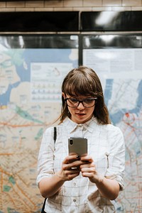 Girl texting while waiting for a train at a subway platform