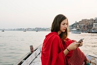 Western woman on a boat texting from the River Ganges