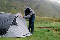 Man zipping his tent while it's raining